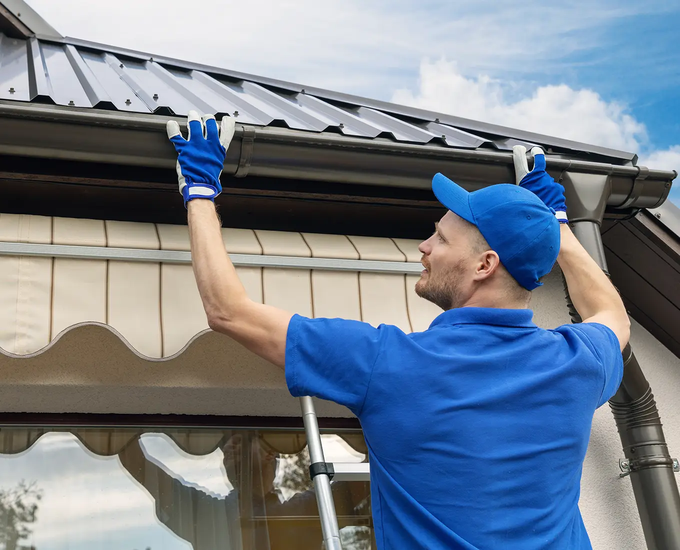 man installing house roof rain gutter system in st louis mo
