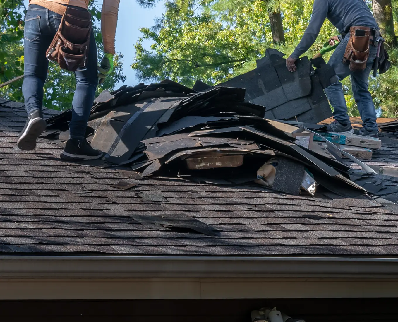 Roofers removing old material from a house in preparation for storm damage repair in st louis mo