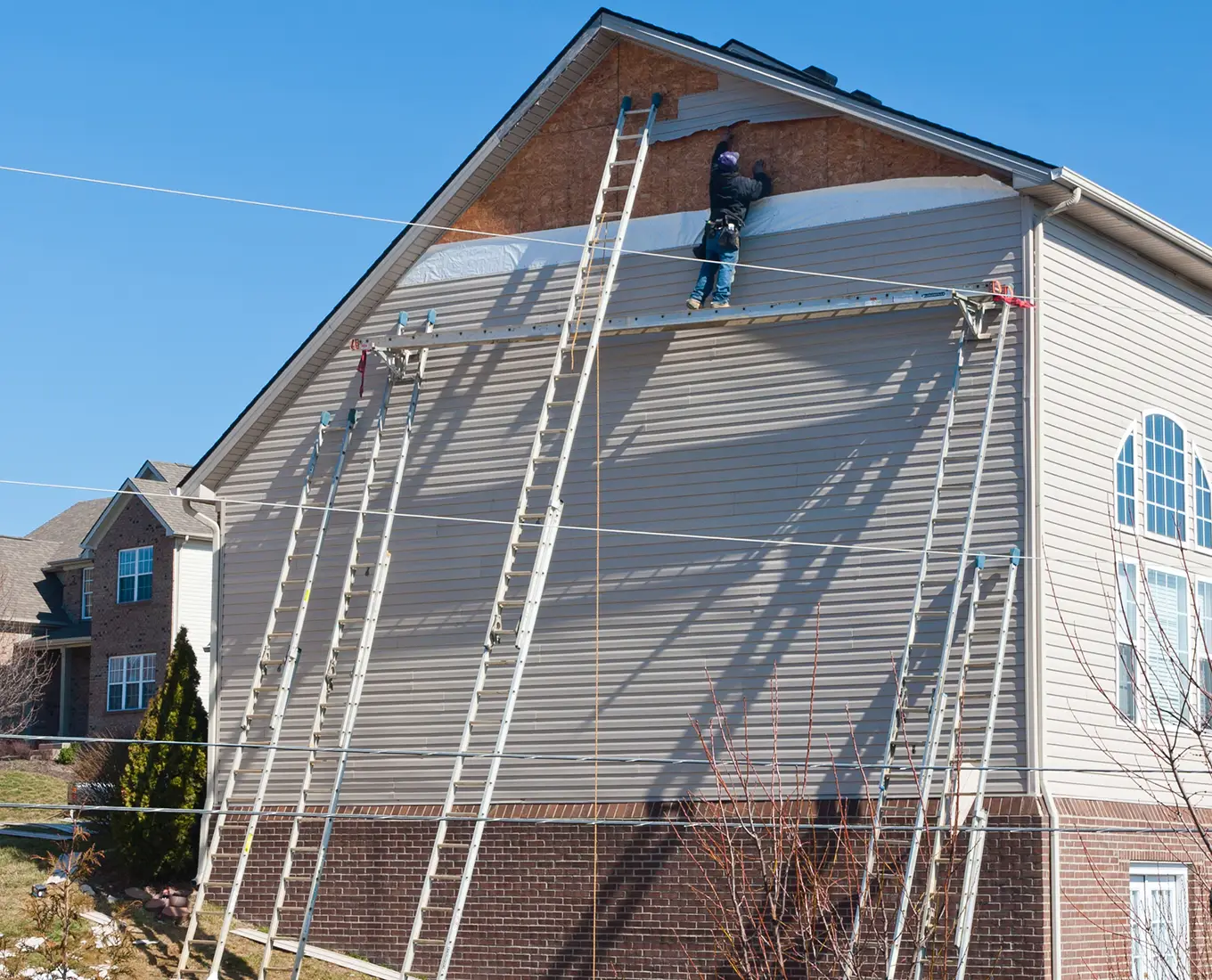 Workers installing plastic siding panels on two story house in st louis mo